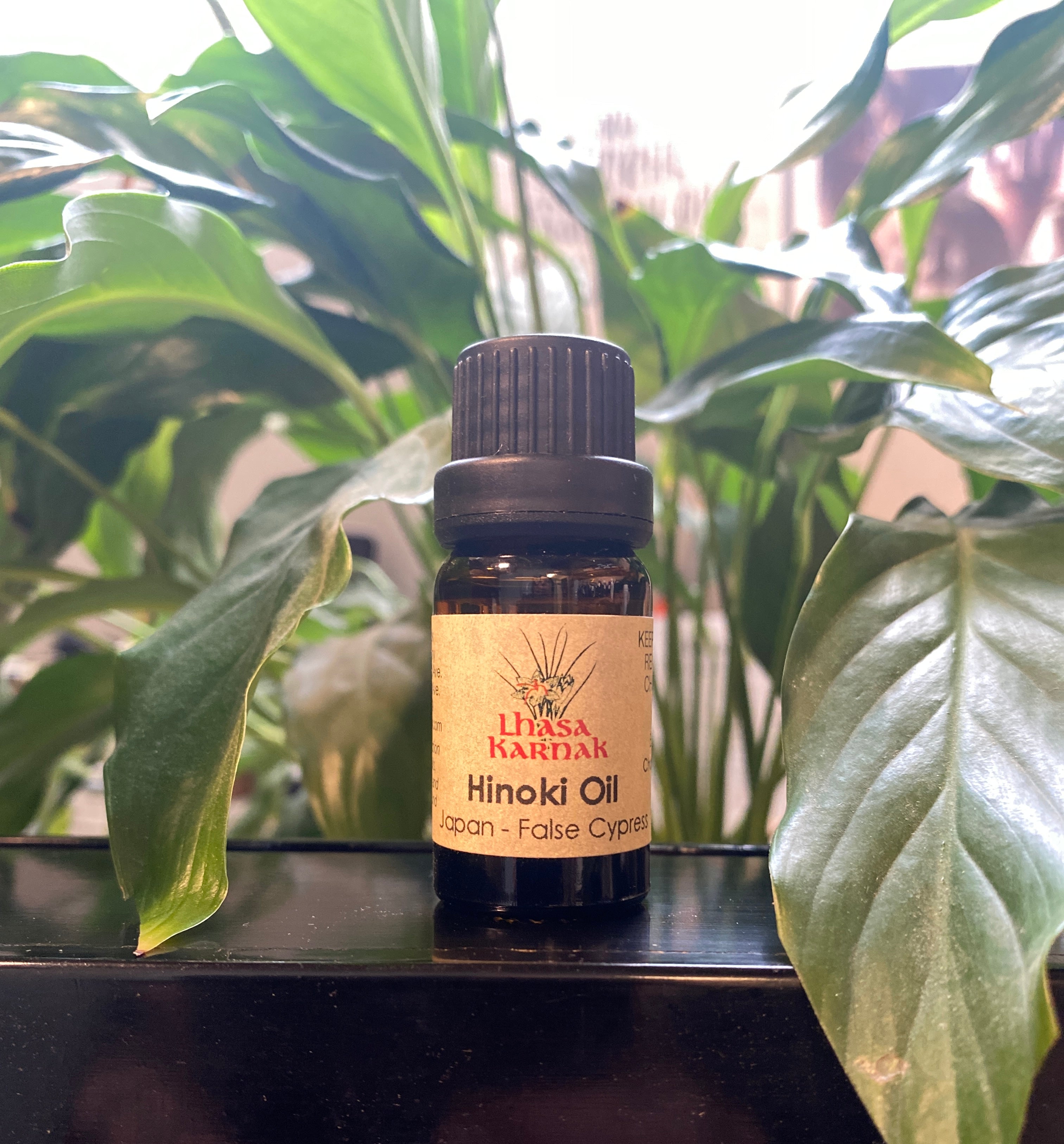Bottle of Hinoki oil with a label on a surface with plants in the background