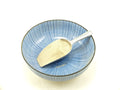 A spoonful of white powder, likely to be pepper, is placed on a blue patterned bowl.